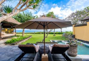 金巴兰AYANA Villas Bali的游泳池旁带遮阳伞和椅子的天井