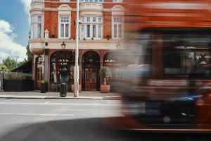 伦敦The Black Lion Pub & Boutique Guesthouse的一辆公共汽车在建筑物前的街道上行驶