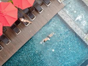 曼谷SKYVIEW Hotel Bangkok - Sukhumvit的在带遮阳伞的游泳池游泳的人