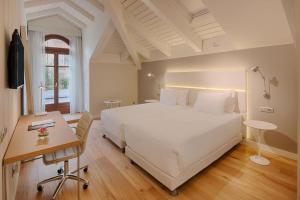 都灵NH Collection Torino Santo Stefano的卧室配有一张白色大床和一张书桌