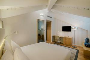 都灵NH Collection Torino Santo Stefano的一间卧室配有一张床、一张书桌和一台电视