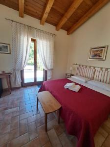 萨杜勒尼亚Casale Terre Rosse Garden的一间卧室配有一张红色的大床和一张桌子