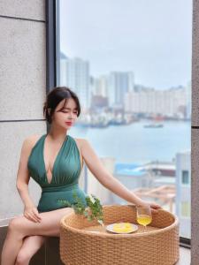 釜山Poolvilla Gaon的坐在桌子旁的穿着绿色衣服的女人,喝杯酒