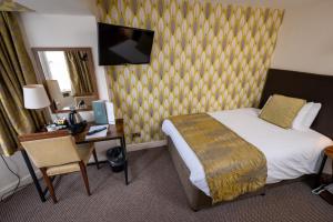 亚特Cross Hands Hotel by Greene King Inns的酒店客房配有一张床、一张书桌和一台电视。