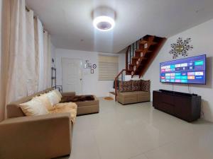 苏比克Cozy Corner at Camella Subic Vista Estates的带沙发和大屏幕电视的客厅