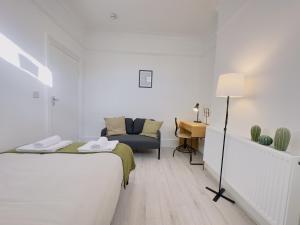 伦敦Leyton House - SleepyLodge的白色的客房配有一张床、一把椅子和一张书桌