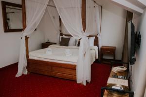莫伊科瓦茨Hotel Serdar的卧室配有带白色窗帘的天蓬床