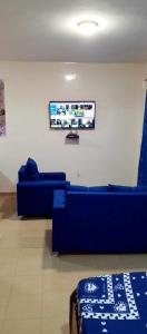 达喀尔RÉSIDENCE NGUARY的客厅配有蓝色的沙发和平面电视。
