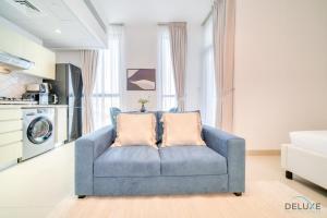 迪拜Placid Studio at Afnan 4 Midtown Dubai Production City by Deluxe Holiday Homes的客厅配有带两个枕头的蓝色沙发