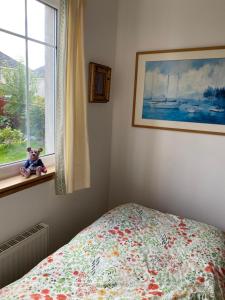 罗塞斯Caledonia House的卧室配有一张床,窗户上摆放着泰迪熊