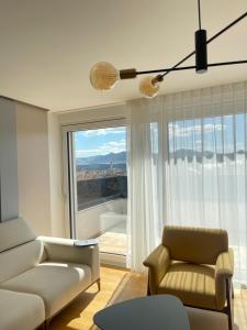 GjakoveGega Apartments的带沙发、椅子和窗户的客厅