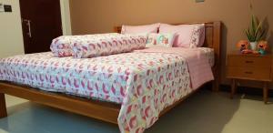 洛坤府BannPordee的一间卧室配有一张带粉色和白色棉被的床