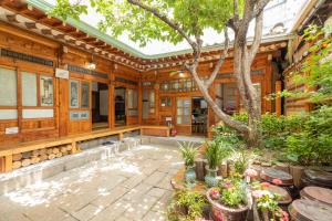 首尔Dongmyo Hanok Sihwadang - Private Korean Style House in the City Center with a Beautiful Garden的庭院里一棵树的老房子