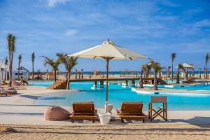 Zāwiyat ‘Abd al Mun‘imLemon Spaces LIGHT- D bay North Coast的一个带椅子和遮阳伞的游泳池的度假酒店