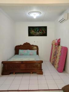 日惹鲁玛优齐旅馆的一间卧室配有一张床和一个粉红色的行李箱