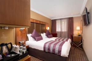 塞文欧克斯唐宁顿庄园酒店的酒店客房配有一张带紫色枕头的大床