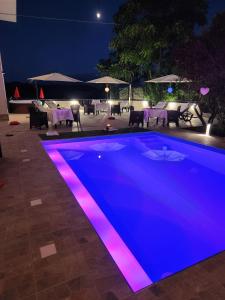 Villa BadessaAndale SuiteSpa的游泳池晚上有紫色灯光
