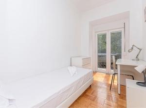 里斯本HOUZE_4 room apartment in Central Lisbon near Zoo的白色卧室配有床和书桌