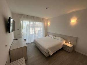 多马索Resort le Vele Suites and Apartments的一间卧室设有一张床、一台电视和一个窗口。