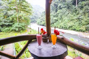 武吉拉旺back to nature ecotourism的一张桌子上放着两杯饮料,享有河景