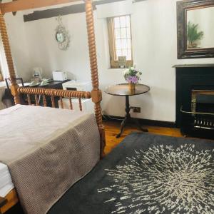 Goffs OakTudor House - Double Room - En suite的客房设有1张床、1张桌子和1个壁炉。
