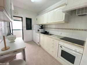 卡武埃鲁Apartamento Amparo-T2 c/piscina的厨房配有白色橱柜和白色家电