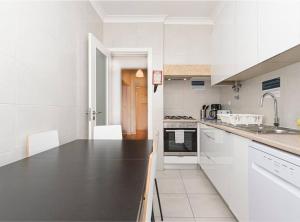 里斯本HOUZE_4 room flat in Central Lisbon near Zoo的厨房配有白色橱柜和黑色台面