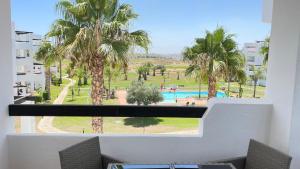 穆尔西亚Apartamento golf-resort murcia的享有游泳池和棕榈树景致的阳台