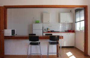 阿索马达布卢姆小屋公寓的厨房配有柜台和3个吧台凳