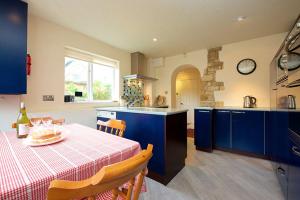 奇平卡姆登Badgers End的厨房配有蓝色橱柜和带桌布的桌子