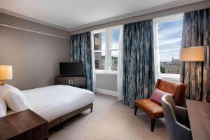 爱丁堡希尔顿爱丁堡卡尔顿酒店的酒店客房带一张床、椅子和窗户