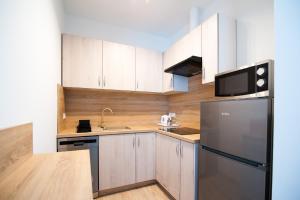 格涅兹诺Apartamenty Emilia的厨房配有白色橱柜和黑色冰箱。