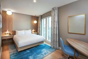 伦敦伦敦超越希尔顿逸林酒店的配有一张床、一张书桌和一扇窗户的酒店客房