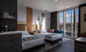 伦敦The Gantry London, Curio Collection By Hilton的酒店客房设有两张床和大窗户。