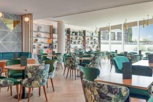 伦敦希尔顿伦敦伊斯灵顿天使酒店的餐厅设有绿色的椅子和桌子以及窗户。