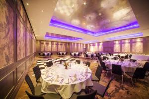 泰晤士河畔金斯顿伦敦泰晤士河畔京士顿希尔顿逸林酒店的宴会厅配有白色桌椅和紫色照明