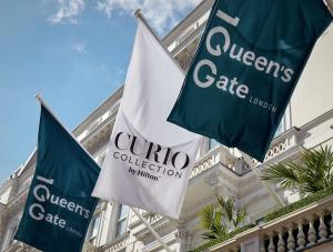伦敦100 Queen’s Gate Hotel London, Curio Collection by Hilton的建筑物前的两面蓝白旗