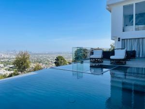 洛杉矶Stunning View Hollywood Hills Guest House的一座房子边缘带两把椅子的游泳池