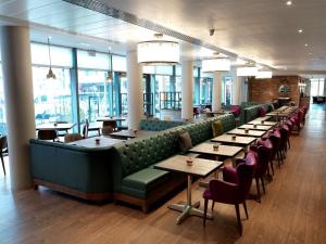 伯明翰希尔顿花园伯明翰布林德雷广场旅馆的餐厅设有长桌子、椅子和窗户。