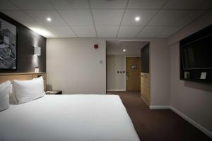 考文垂DoubleTree by Hilton Coventry Building Society Arena的卧室配有一张白色大床和电视。