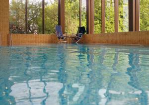 谢菲尔德希尔顿谢菲尔德公园双树酒店的大楼内一个带两把椅子的游泳池