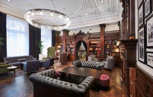 利物浦利物浦希尔顿逸林酒店的一个带皮革家具和吊灯的图书馆