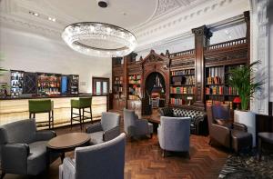 利物浦利物浦希尔顿逸林酒店的一个带桌椅和吊灯的图书馆