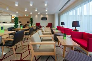 霍利希尔顿汉普顿伦敦盖特威克机场酒店的一间设有桌子和红色椅子的等候室