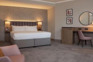 达特福德达特福德大桥希尔顿逸林酒店的一间卧室配有一张床、一张书桌和一面镜子