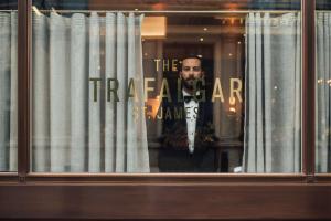 伦敦特拉法加圣詹姆斯，伦敦希尔顿Curio Collection酒店的站在窗户上,有标牌的人