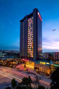 伊斯坦布尔伊斯坦布尔阿塔图尔克机场希尔顿花园酒店的一座有灯光的建筑,飞机飞越城市