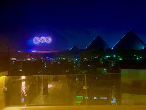 开罗Celia Pyramids View inn的享有金字塔的景色,晚上有紫色的灯光