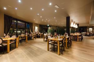 索斯图尼恩DoubleTree by Hilton Royal Parc Soestduinen的餐厅设有木桌、椅子和窗户。