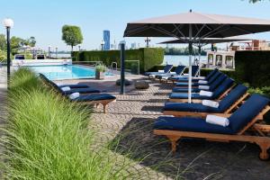 维也纳Hilton Vienna Waterfront的游泳池旁一排带遮阳伞的躺椅